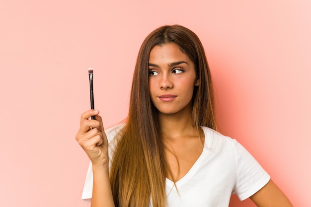 Giovane donna caucasica che tiene un eyebrush isolato