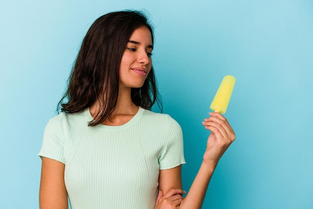 Giovane donna caucasica che tiene un gelato isolato su sfondo blu