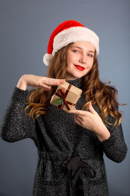 Giovane donna caucasica che tiene un regalo su sfondo grigio isolato