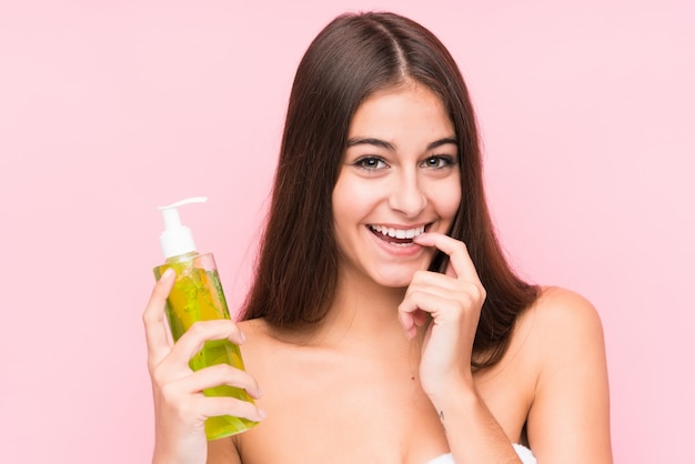 Giovane donna caucasica che tiene una crema idratante con aloe vera rilassato pensando a qualcosa