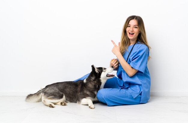 Giovane donna caucasica con il cane sopra la parete isolata