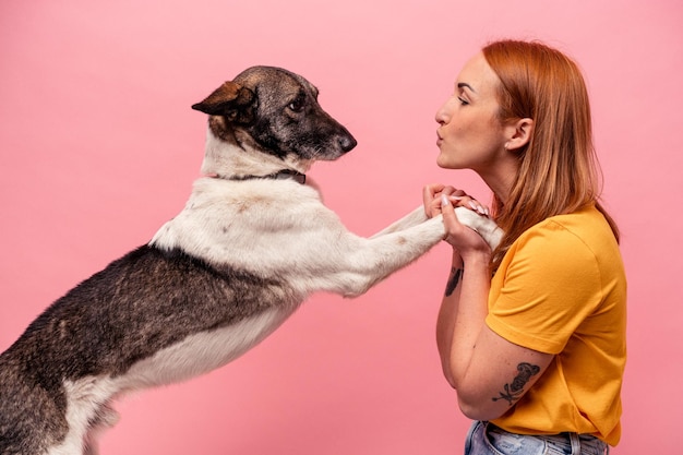 Giovane donna caucasica con il suo cane isolato su sfondo rosa