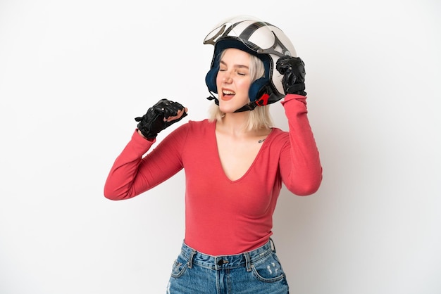 Giovane donna caucasica con un casco da motociclista isolato su sfondo bianco che celebra una vittoria