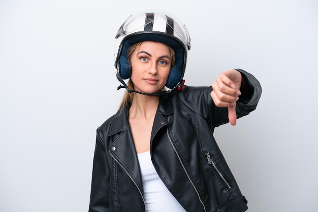 Giovane donna caucasica con un casco da motociclista isolato su sfondo bianco che mostra il pollice verso il basso con espressione negativa