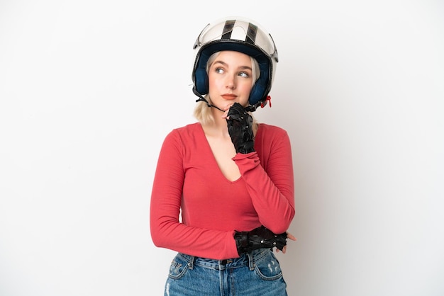Giovane donna caucasica con un casco da motociclista isolato su sfondo bianco e alzando lo sguardo