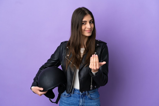 Giovane donna caucasica con un casco da motociclista isolato su sfondo viola