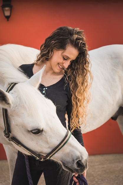 Giovane donna caucasica con un cavallo in un centro ippico