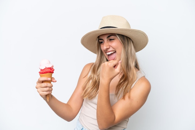 Giovane donna caucasica con un gelato alla cornetta isolato su sfondo bianco che celebra una vittoria