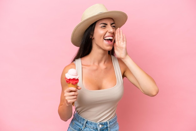 Giovane donna caucasica con un gelato di cornetta isolato su sfondo rosa