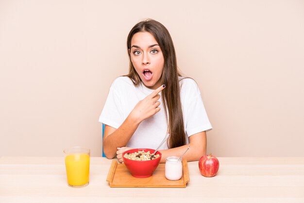 Giovane donna caucasica con una colazione isolata che punta al lato