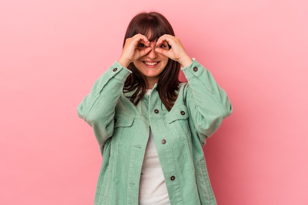 Giovane donna caucasica curvy isolata su fondo rosa che mostra il segno giusto sopra gli occhi