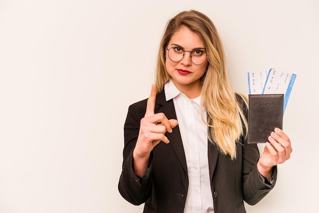 Giovane donna caucasica d'affari in possesso di un passaporto isolato su sfondo bianco che mostra il numero uno con il dito