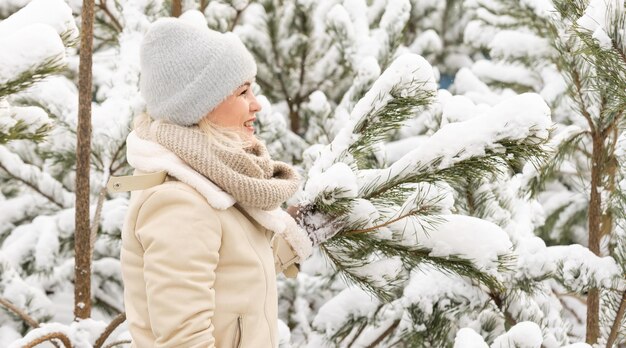 Giovane donna caucasica felice che ride e rami di pino nella foresta d'inverno. Emozioni positive, camminando con tempo nevoso