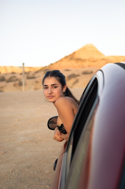 Giovane donna caucasica fuori dal finestrino di una macchina nel deserto di Bardenas Reales. Navarra, Paesi Baschi.