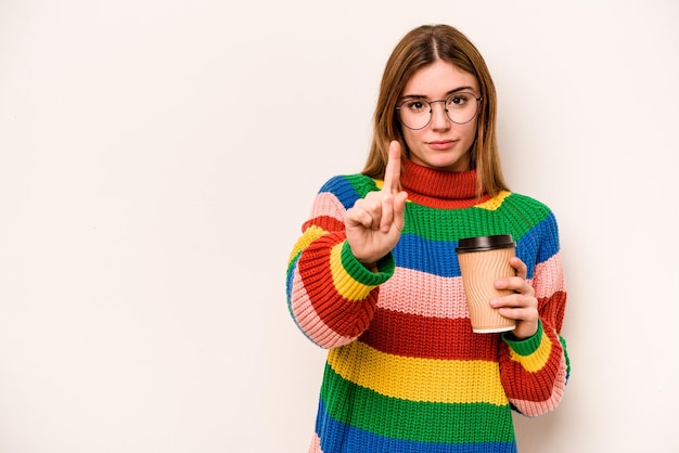 Giovane donna caucasica in possesso di un caffè da asporto isolato su sfondo bianco che mostra il numero uno con il dito