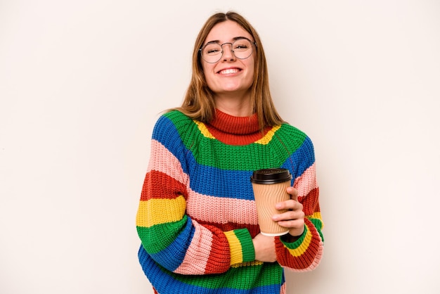 Giovane donna caucasica in possesso di un caffè da asporto isolato su sfondo bianco ridendo e divertendosi