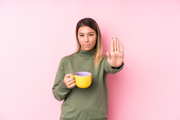 Giovane donna caucasica in possesso di un caffè in piedi con la mano tesa mostrando il segnale di stop, impedendoti.
