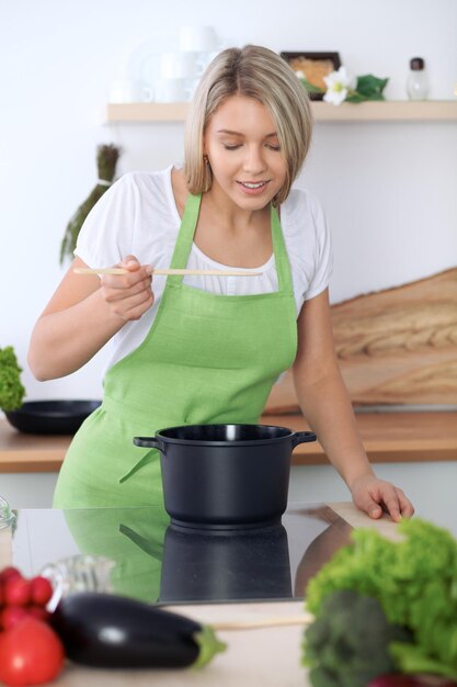 Giovane donna caucasica in un grembiule verde che cucina in cucina