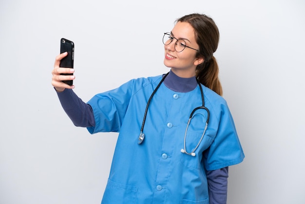 Giovane donna caucasica infermiera isolata su sfondo bianco che fa un selfie