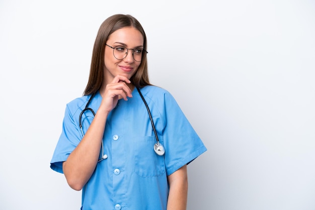 Giovane donna caucasica infermiera isolata su sfondo bianco che guarda al lato