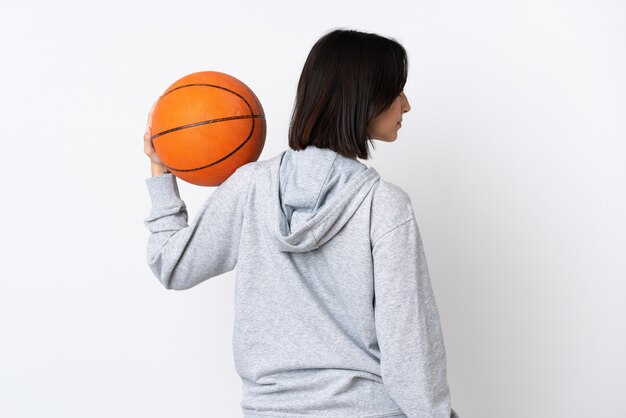 Giovane donna caucasica isolata giocando a basket nella posizione posteriore