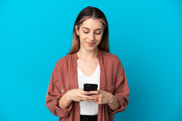 Giovane donna caucasica isolata inviando un messaggio o un messaggio di posta elettronica con il cellulare