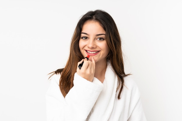 Giovane donna caucasica isolata su bianco che tiene rossetto rosso