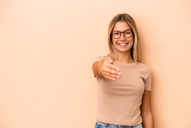 Giovane donna caucasica isolata su fondo beige che sorride e che alza pollice su