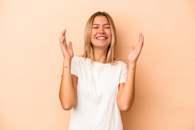 Giovane donna caucasica isolata su fondo beige ridendo gioiosa molto. Concetto di felicità.