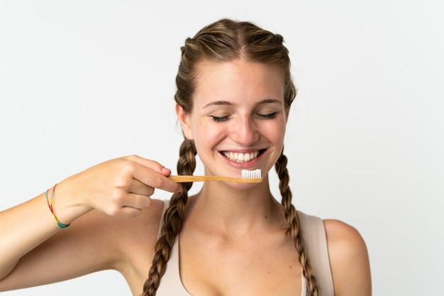 Giovane donna caucasica isolata su priorità bassa bianca con uno spazzolino da denti e l'espressione felice