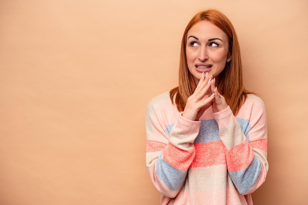 Giovane donna caucasica isolata su sfondo beige che compone un piano in mente per creare un'idea