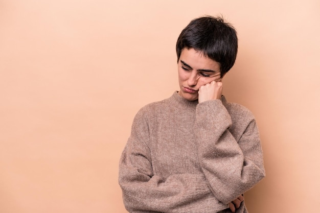 Giovane donna caucasica isolata su sfondo beige che si sente triste e pensierosa guardando lo spazio della copia