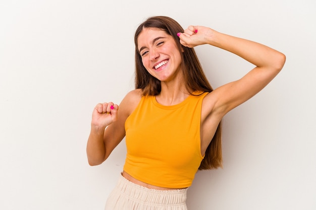 Giovane donna caucasica isolata su sfondo bianco che celebra un giorno speciale, salta e alza le braccia con energia.