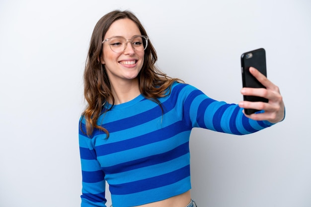 Giovane donna caucasica isolata su sfondo bianco che fa un selfie con il cellulare