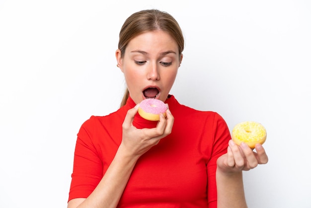 Giovane donna caucasica isolata su sfondo bianco che mangia una ciambella