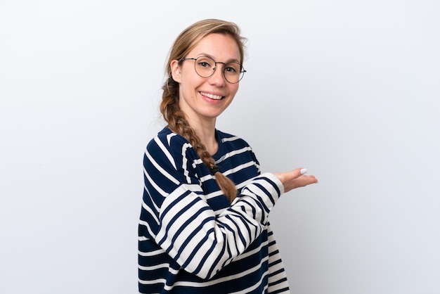 Giovane donna caucasica isolata su sfondo bianco che presenta un'idea mentre guarda sorridendo verso