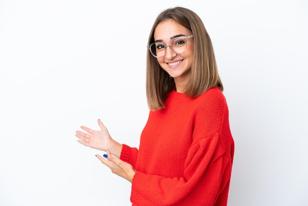 Giovane donna caucasica isolata su sfondo bianco Con gli occhiali e presentare qualcosa