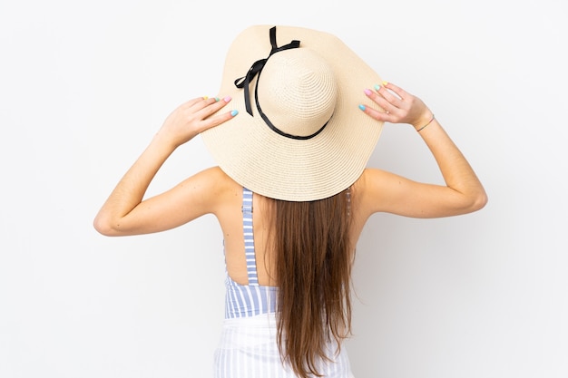 Giovane donna caucasica isolata su sfondo bianco in costume da bagno e in posizione posteriore