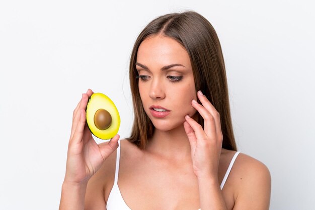 Giovane donna caucasica isolata su sfondo bianco in possesso di un avocado Close up ritratto