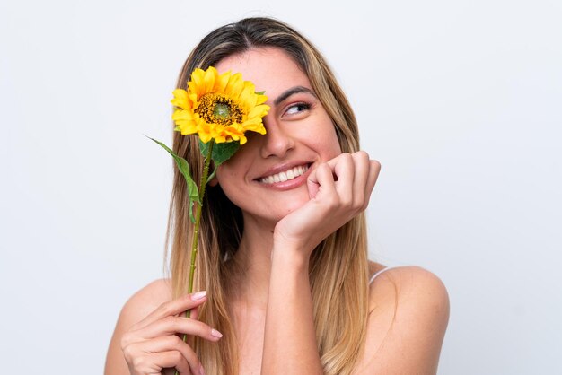 Giovane donna caucasica isolata su sfondo bianco in possesso di un girasole mentre sorride Close up ritratto