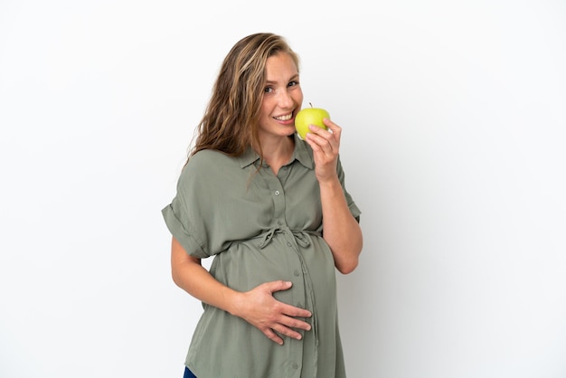 Giovane donna caucasica isolata su sfondo bianco incinta e con in mano una mela