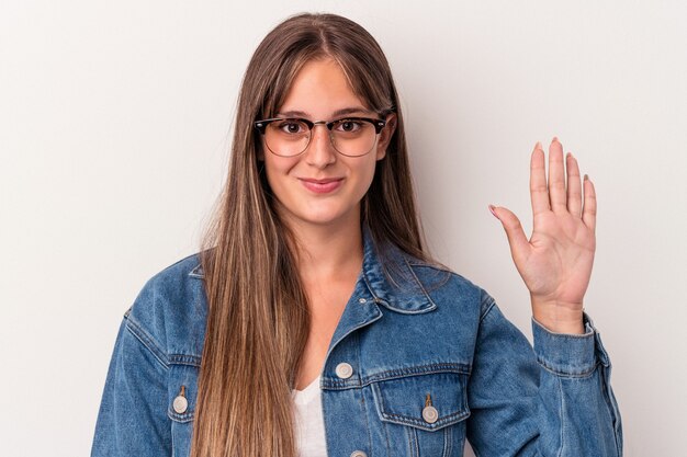 Giovane donna caucasica isolata su sfondo bianco sorridente allegro che mostra il numero cinque con le dita.