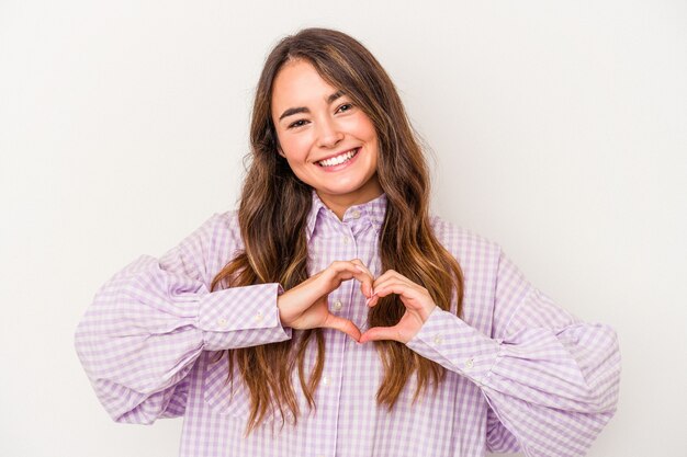 Giovane donna caucasica isolata su sfondo bianco sorridente e mostrando una forma di cuore con le mani.