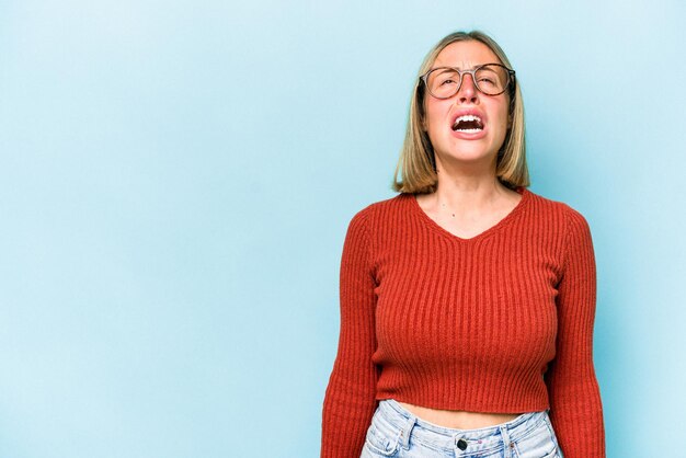 Giovane donna caucasica isolata su sfondo blu che grida concetto di rabbia molto arrabbiato frustrato