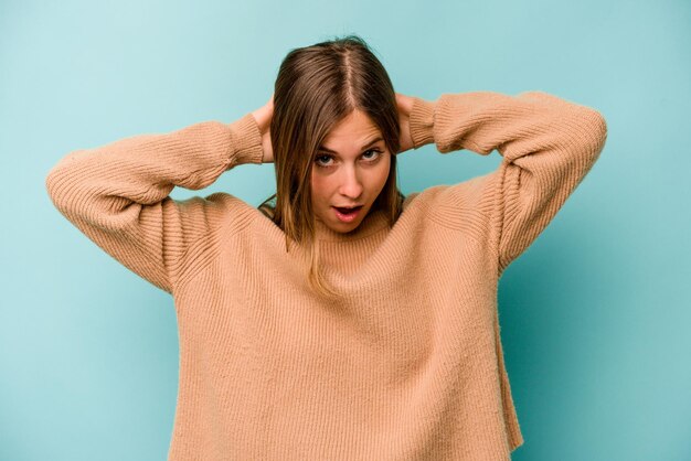 Giovane donna caucasica isolata su sfondo blu che urla molto eccitata appassionata soddisfatta di qualcosa