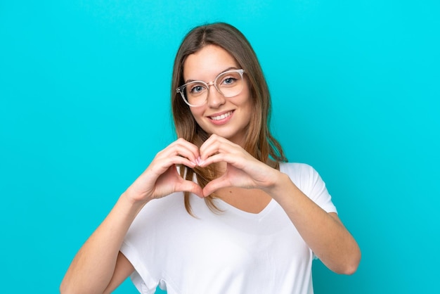 Giovane donna caucasica isolata su sfondo blu Con gli occhiali che fanno il cuore con le mani