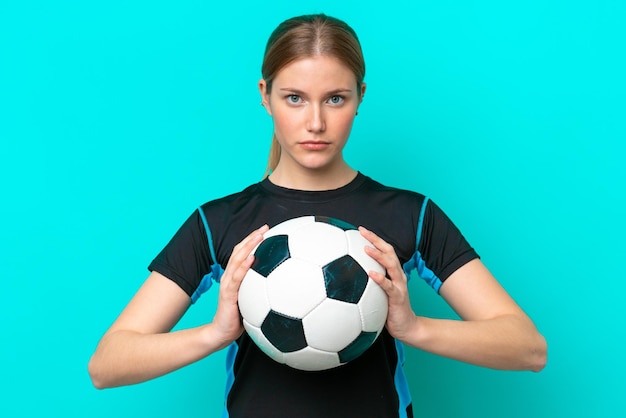 Giovane donna caucasica isolata su sfondo blu con pallone da calcio