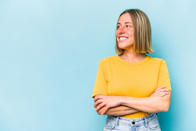 Giovane donna caucasica isolata su sfondo blu sorridente fiduciosa con le braccia incrociate