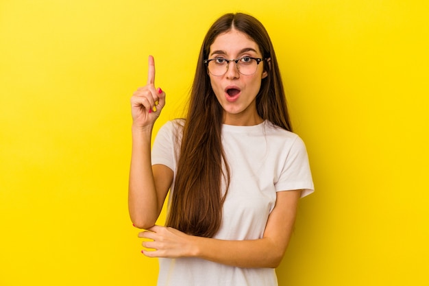 Giovane donna caucasica isolata su sfondo giallo con qualche grande idea, concetto di creatività.