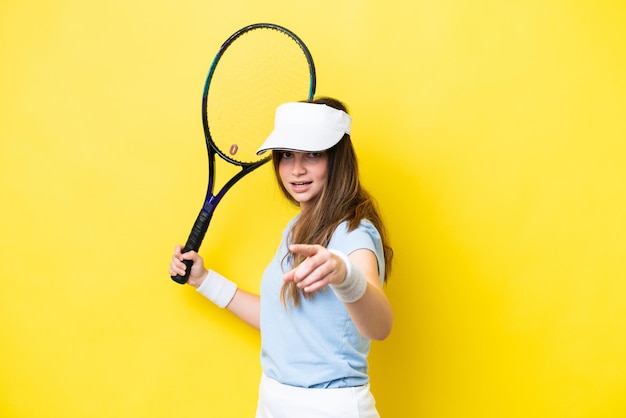 Giovane donna caucasica isolata su sfondo giallo giocando a tennis